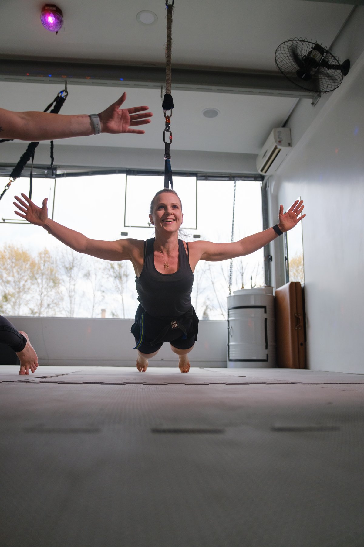 Aluna suspensa no bungee, braços abertos
